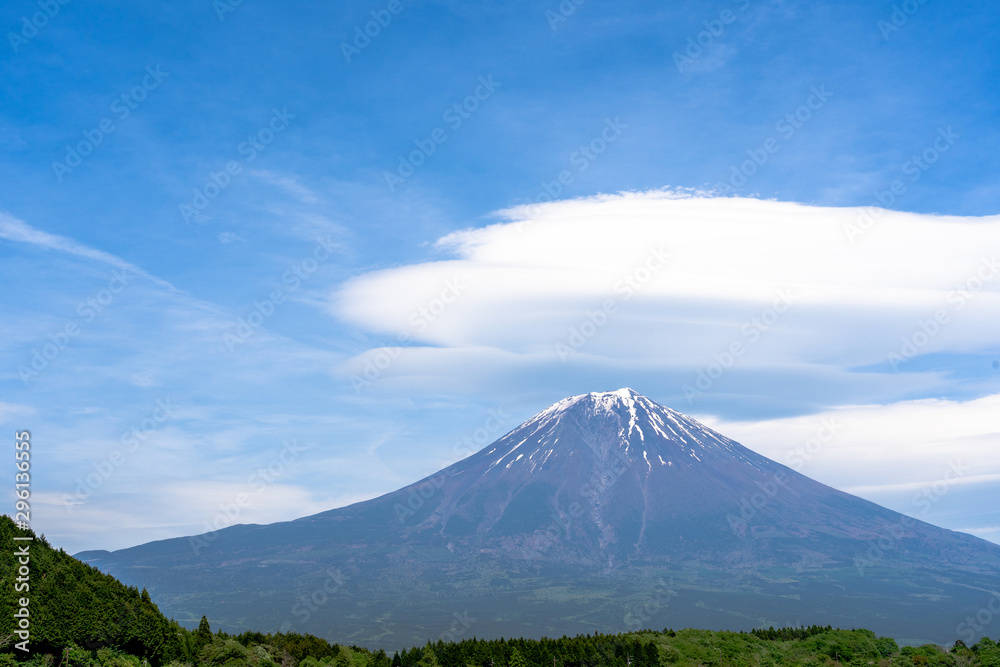 Fuji mountain with cloudy hat on top , amazing clouds on blue sky background spot view at Lake Tanuki (Tanuki-ko) in morning time near small hill and green forest foreground ,Mount Fuji , Fujinomiya,
