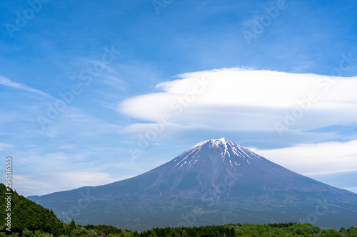 Fuji mountain with cloudy hat on top , amazing clouds on blue sky background spot view at Lake Tanuki (Tanuki-ko) in morning time near small hill and green forest foreground ,Mount Fuji , Fujinomiya,