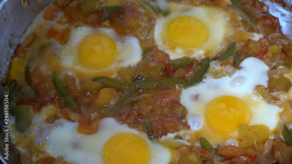 Tasty and healthy shakshuka in a frying pan. Eggs poached in spicy tomato pepper sauce. Delicious shakshuka - fried eggs, onion, bell pepper, tomatoes, chili and spices in pan, close up Tasty and healthy shakshuka in a frying pan. Eggs poached in spicy tomato pepper sauce. Delicious shakshuka - fried eggs, onion, bell pepper, tomatoes, chili and spices in pan, close up