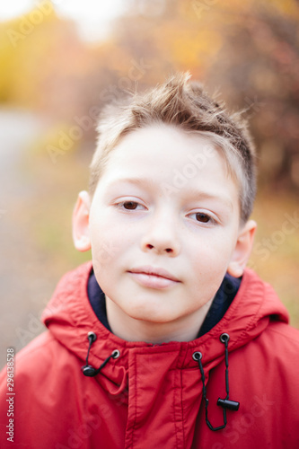 Portrait of cute boy looking at camera  wearing red jacket  isolated on autumn background