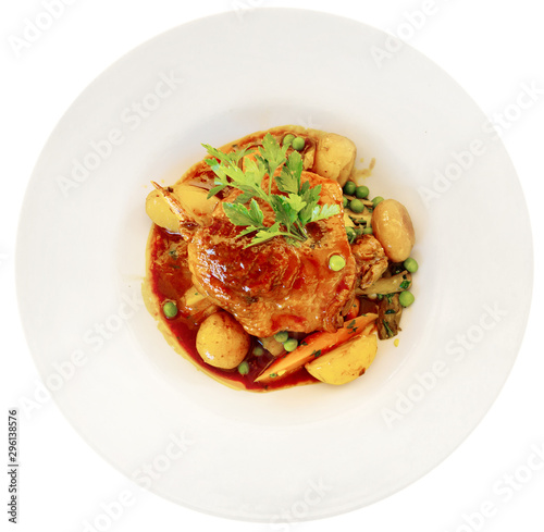 Roasted duck leg with baked potatoes, green peas, parsley and tomatoes. French cuisine