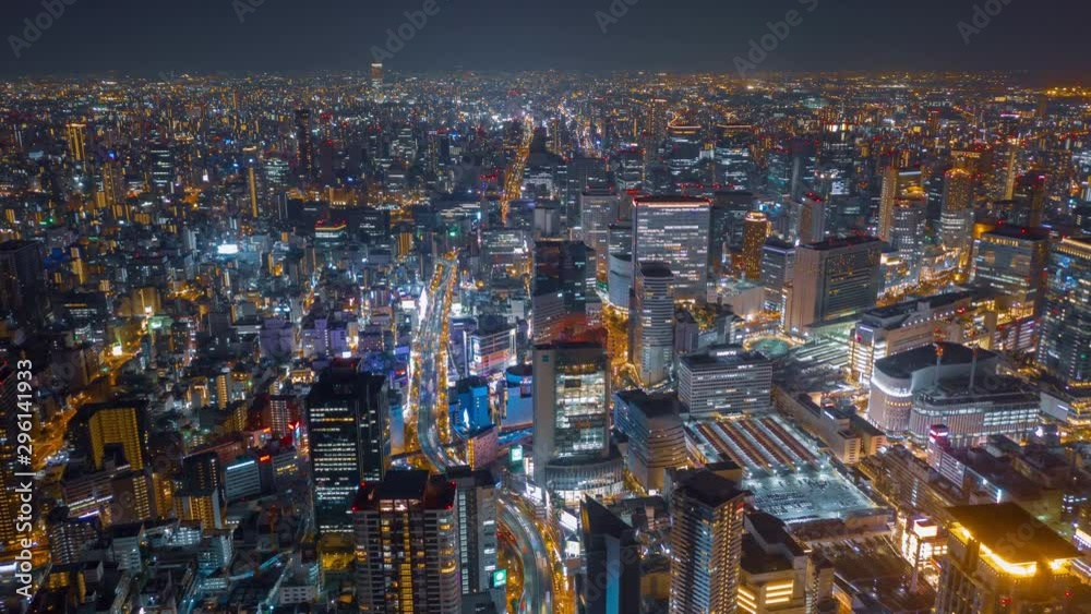 Aerial night hyper lapse over Osaka city with Umeda(Osaka) train station and many skyscraper building and vehicles.