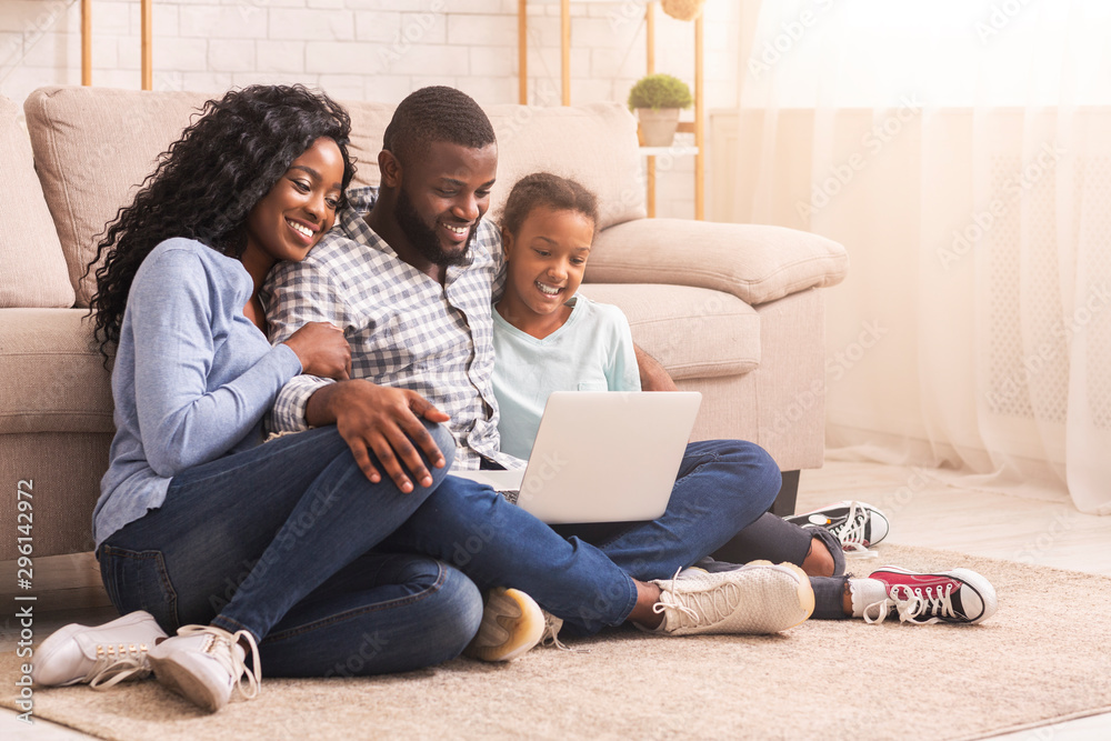 Father, mother and daughter using laptop at home together Father, mother and daughter using laptop at home together