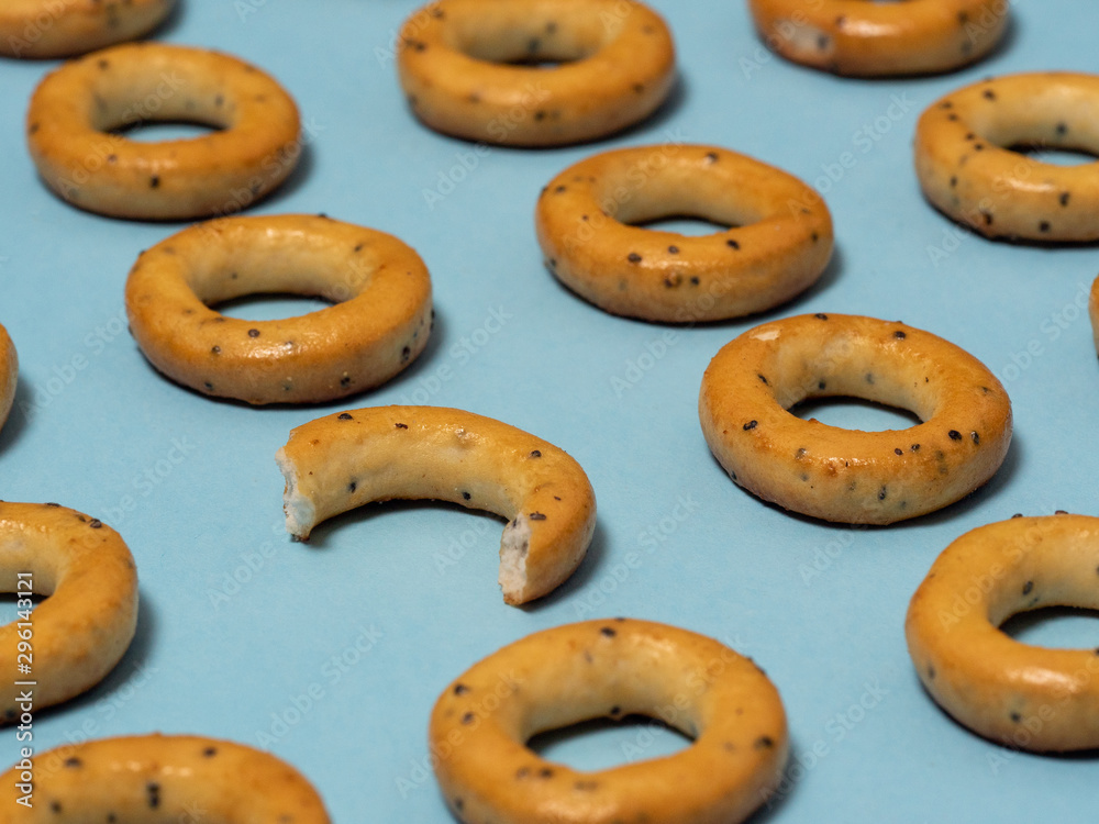 Pattern of edible products. bagels with poppy seeds lie on a blue paper background. One of them is different from the others