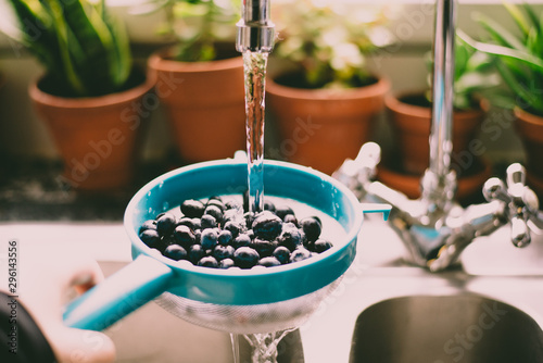 blueberries washed under running water in the sink