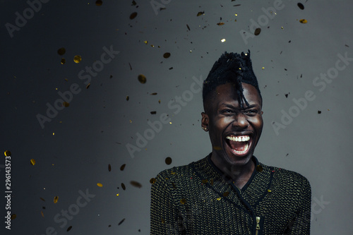 Portrait of an excited, happy young man laughing and celebrating, with gold confetti falling