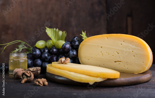 Dutch hard cheese Maasdam or Emmentaler, with honey fruit and grape