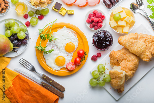Homemade breakfast with sunny side up fried egg croissant toast coffee fruits vegetable and orange juice in top view with copy space. Delicious homemade american breakfast concept for background. Amer