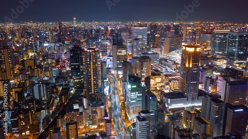 Aerial night hyper lapse over Osaka city with Umeda (Osaka) train station and many skyscraper building and vehicles. photo