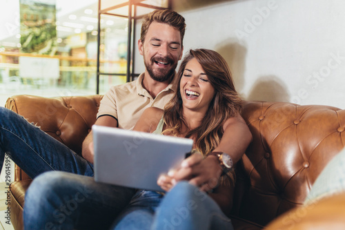 Flirting couple in cafe using digital tablet