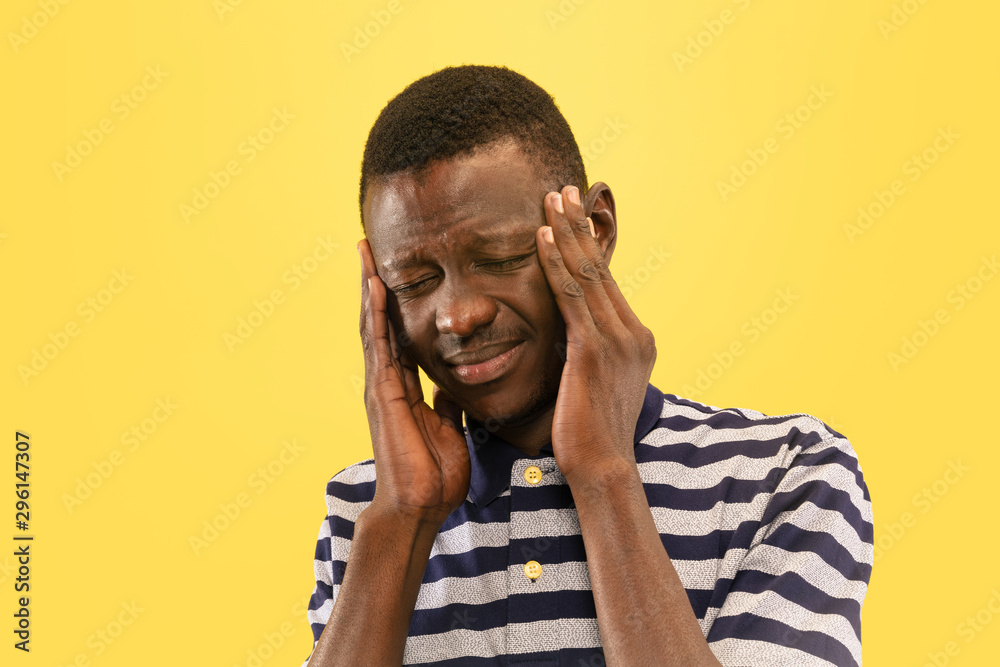 Young african-american man with headcache isolated on yellow studio background, facial expression. Beautiful male half-lenght portrait. Concept of human emotions, facial expression. Young african-american man with headcache isolated on yellow studio background, facial expression. Beautiful male half-lenght portrait. Concept of human emotions, facial expression.