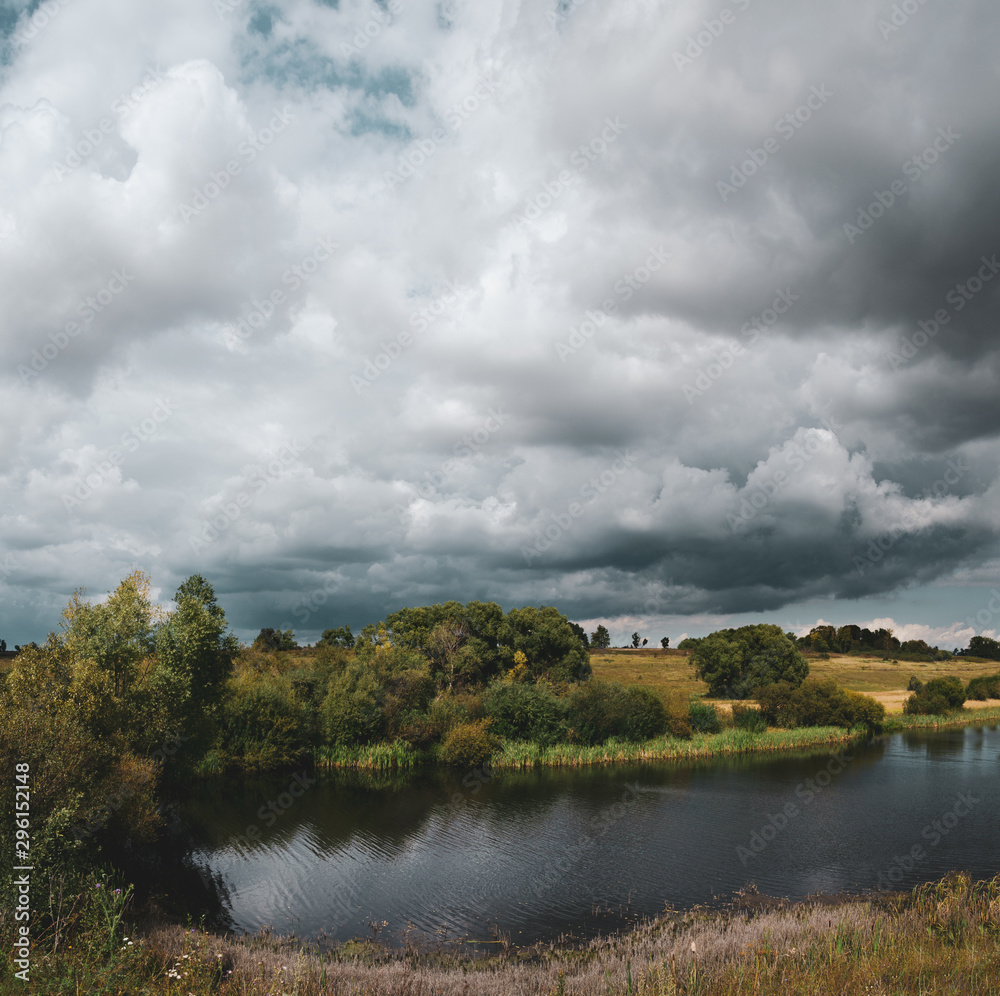 Beautiful view of river and dark stormy clouds over the land