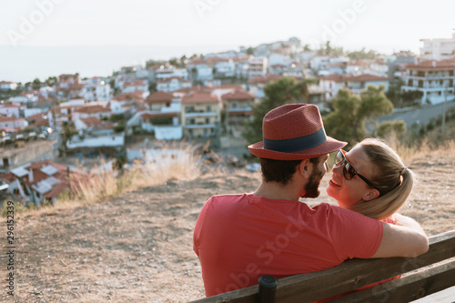 Young couple in love enjoying the view of the town and sunset from a hill in Greece