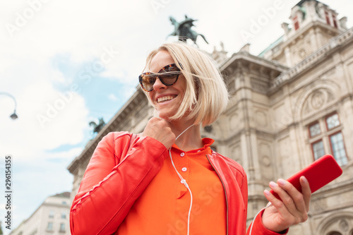 Canvas Print Young girl listens to music with headphones in front of Vienna State Opera, Aust