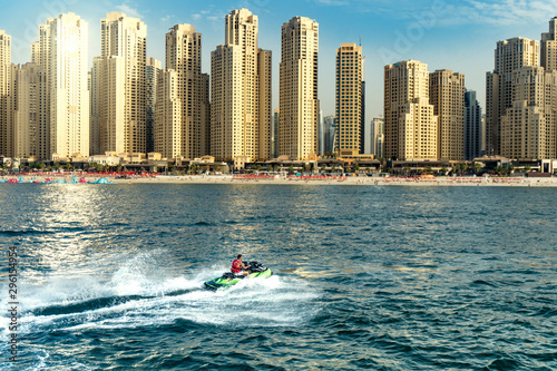 man bashing the waves on the sea with dubay skyline in the background