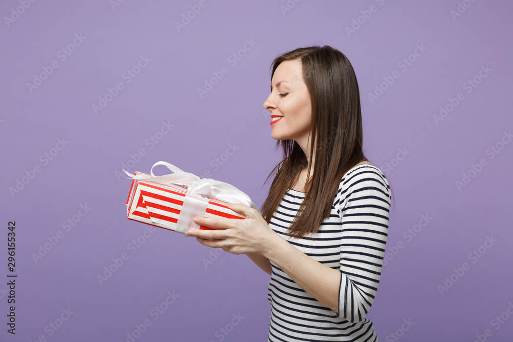 Young brunette woman girl in casual striped clothes posing isolated on violet purple background studio portrait. People sincere emotions lifestyle concept. Mock up copy space. Hold gift present box. Young brunette woman girl in casual striped clothes posing isolated on violet purple background studio portrait. People sincere emotions lifestyle concept. Mock up copy space. Hold gift present box.