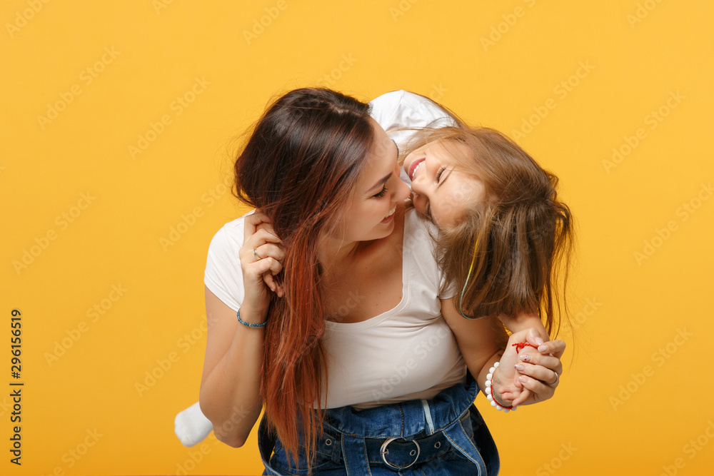 Woman in light clothes have fun with cute child baby girl 4-5 years old. Mommy little kid daughter isolated on yellow background studio portrait. Mother's Day love family parenthood childhood concept. Woman in light clothes have fun with cute child baby girl 4-5 years old. Mommy little kid daughter isolated on yellow background studio portrait. Mother's Day love family parenthood childhood concept.