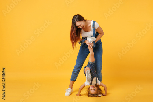 Woman in light clothes have fun with cute child baby girl 4-5 years old. Mommy little kid daughter isolated on yellow background studio portrait. Mother's Day love family parenthood childhood concept.