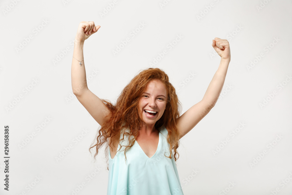 Young laughing redhead woman girl in casual light clothes posing isolated on white wall background. People sincere emotions lifestyle concept. Mock up copy space. Rising hands, doing winner gesture. Young laughing redhead woman girl in casual light clothes posing isolated on white wall background. People sincere emotions lifestyle concept. Mock up copy space. Rising hands, doing winner gesture.