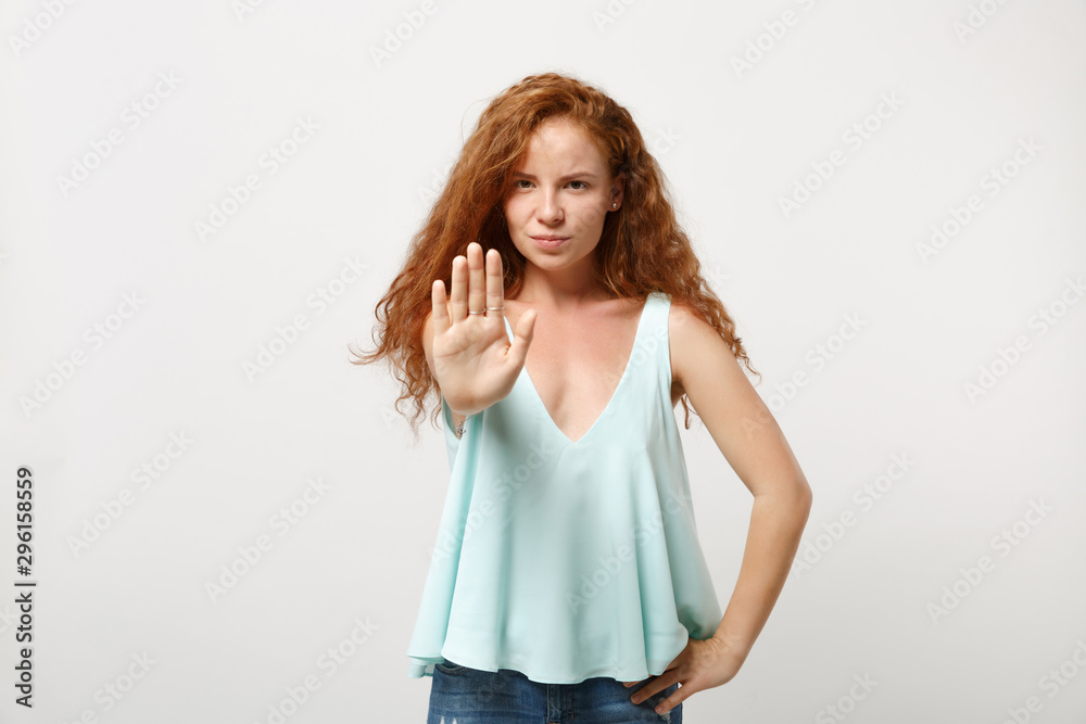 Young serious redhead woman girl in casual light clothes posing isolated on white wall background, studio portrait. People lifestyle concept. Mock up copy space. Showing stop gesture with palm. Young serious redhead woman girl in casual light clothes posing isolated on white wall background, studio portrait. People lifestyle concept. Mock up copy space. Showing stop gesture with palm.
