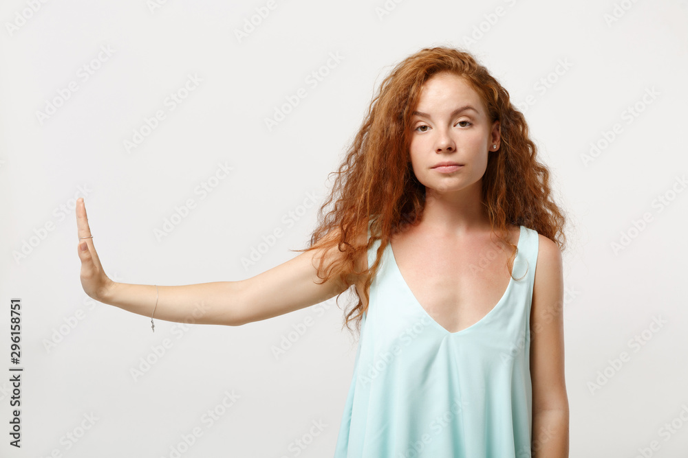 Young serious redhead woman girl in casual light clothes posing isolated on white wall background studio portrait. People lifestyle concept. Mock up copy space. Showing stop gesture aside with palm.