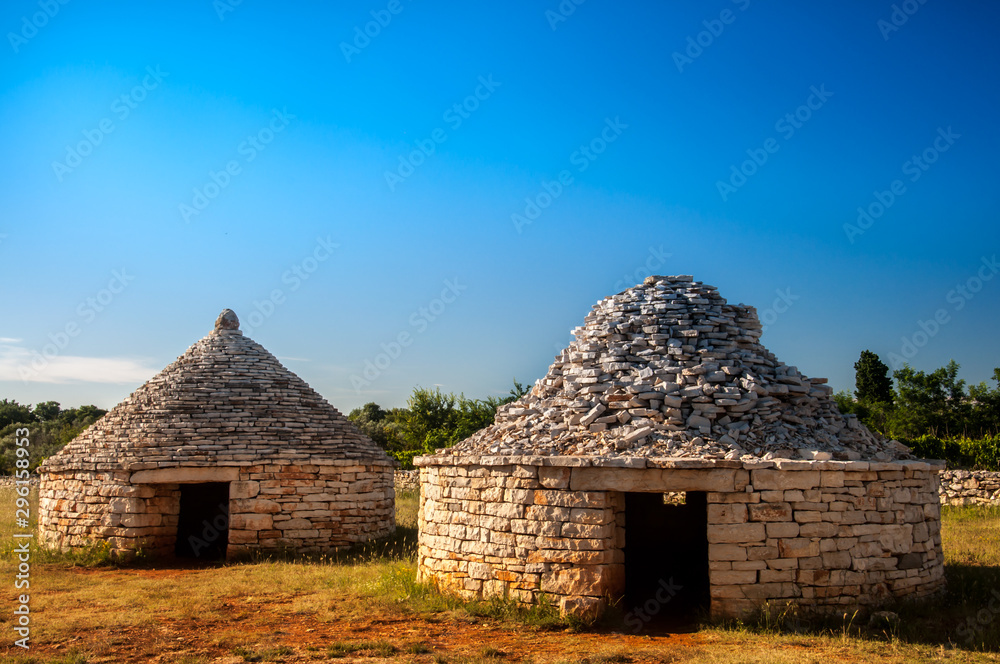 Naklejka premium Three traditional istrian huts - Kazun, with blue sky in background.