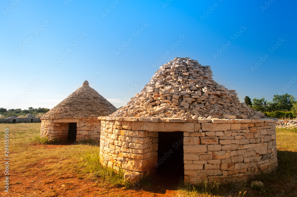 Two traditional istrian huts - Kazun, with blue sky in background.