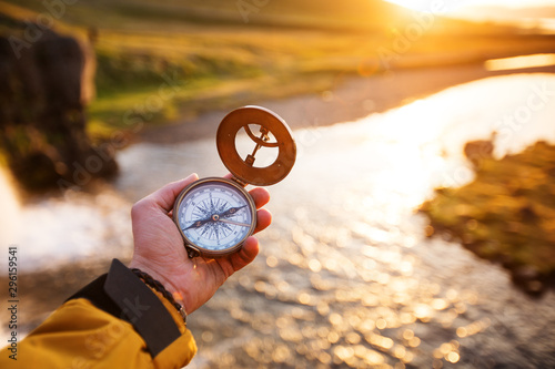Beautiful landscape with old compass on traveler's hand. Traveling concept. photo