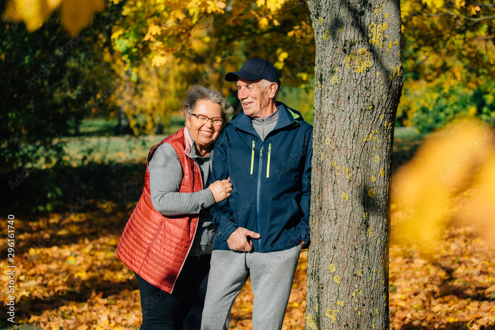 Pretty senior couple having fun in autumn park. Mature woman and old man resting outdoors.