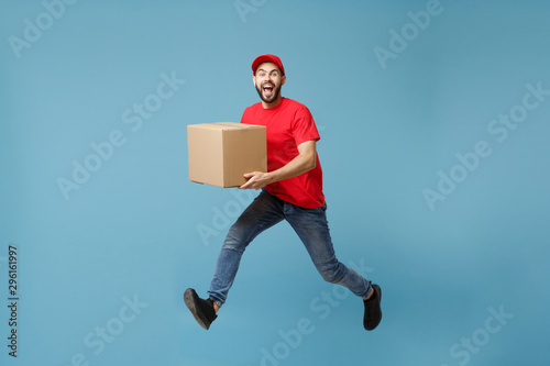 Obraz na plátně Delivery man in red uniform isolated on blue background, studio portrait