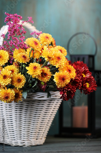 Autumn background with beautiful flowers in basket on the table.