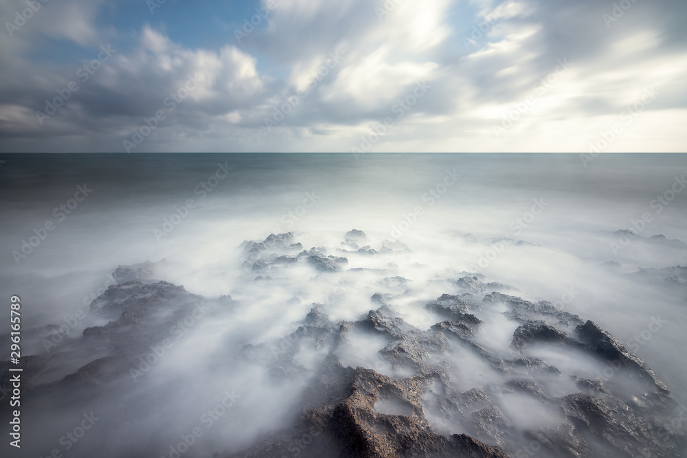 Idyllic rocks bathed by an ethereal sea under a spectacular cloudscape