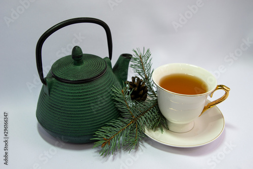 Cast iron green small teapot. White porcelain Cup . White saucer. Christmas tree. white background. The concept of the celebration. relax