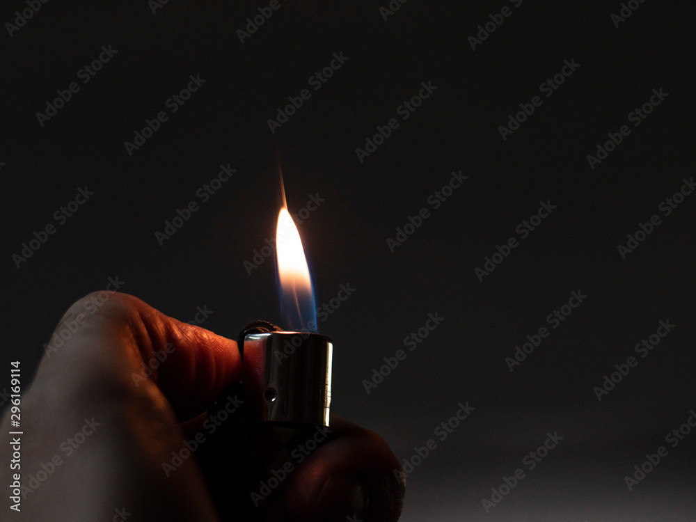 Men's hands hold lighters, fire from cigarette. Burning lighter a man's hand. Blue flame of a lighter. The texture of the skin of a human hand. Gas lighter in action Stock-foto