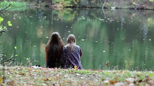 Vape lgbt teenagers. Bisexual lesbian young caucasian teenage girls in casual clothes vape electronic cigarette near the river on the street in the park in the autumn evening. Bad habit.