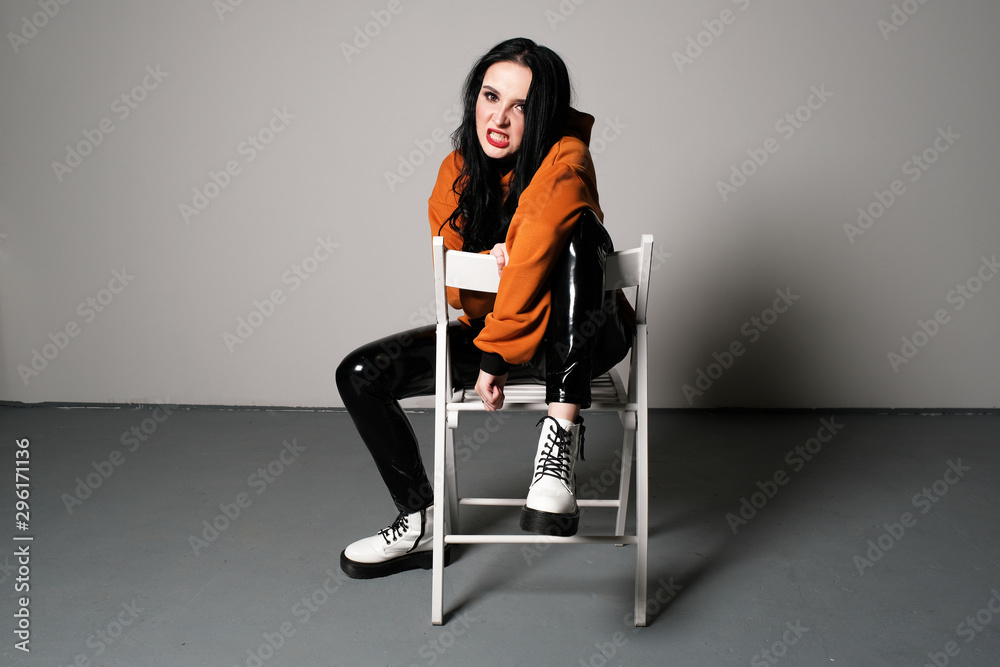 A young girl with aggressive emotion is sitting on a chair. Human emotions A young girl with aggressive emotion is sitting on a chair. Human emotions