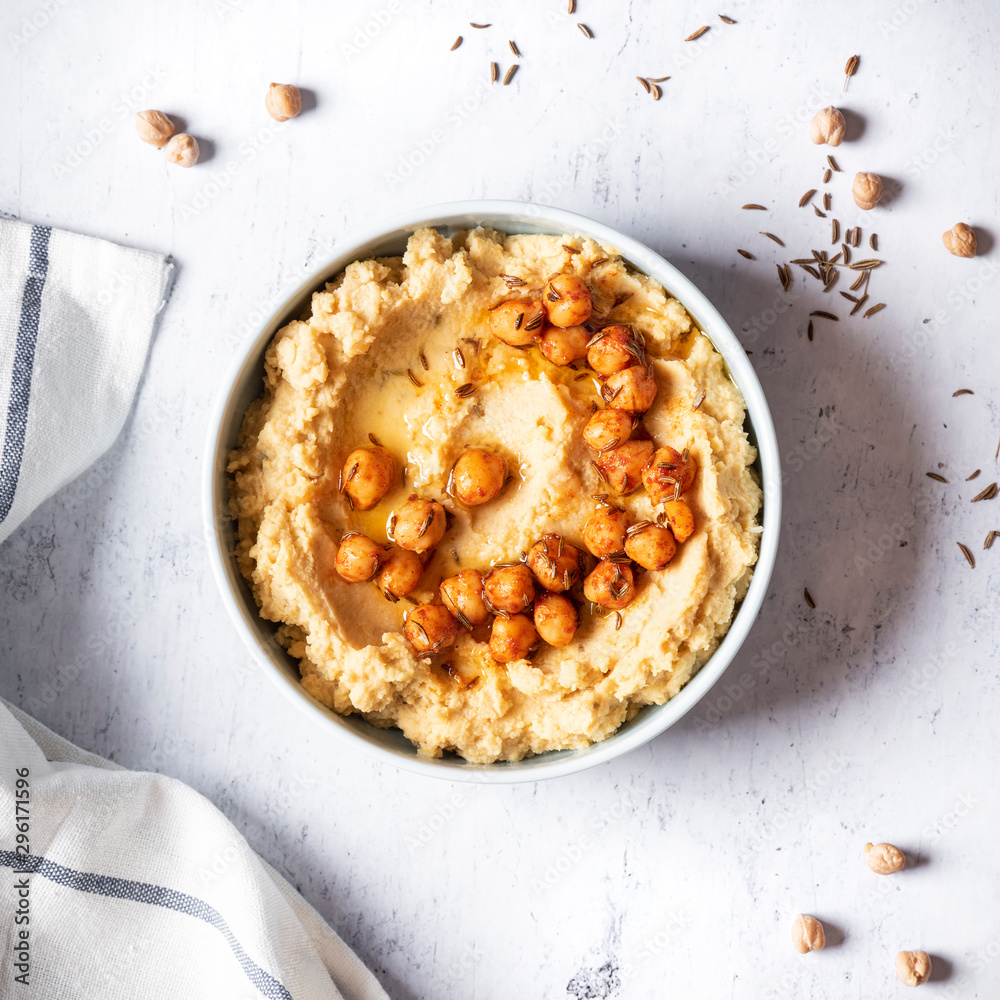 Hummus with olive oil and chickpeas in a ceramic bowl on a light grey background Hummus with olive oil and chickpeas in a ceramic bowl on a light grey background