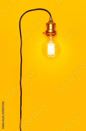 Vintage fashionable edison lamp on bright yellow background. Top view flat lay copy space. Creative idea concept, designer lamp, modern interior item. Lighting, electricity, background with lamp