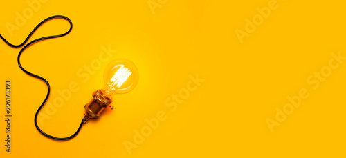 Slika na platnu Vintage fashionable edison lamp on bright yellow background