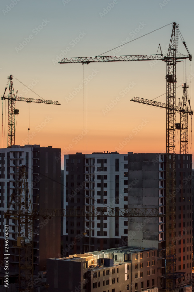 Industrial construction cranes and buildings at sunset