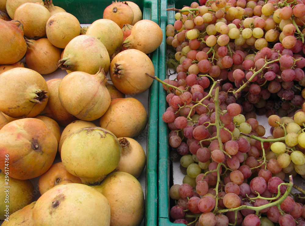 Fall farmers market display of white pomegranates, red flame grapes