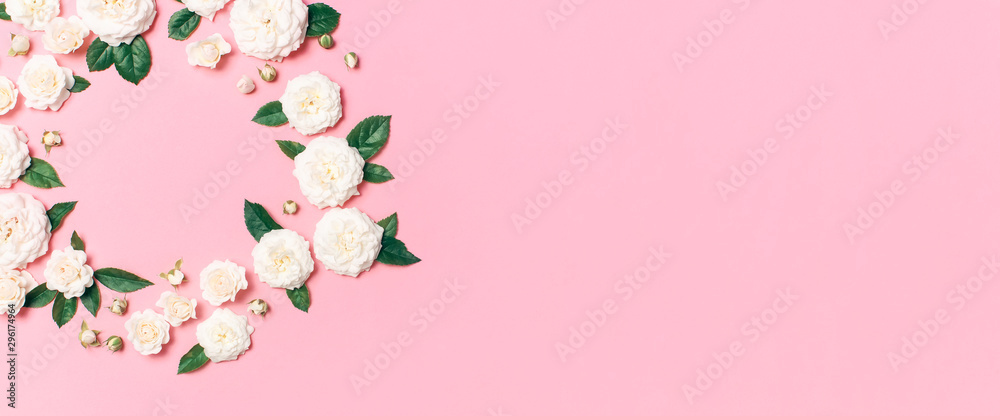 Flowers composition. Frame in the form of circle of white fresh roses and green leaves on gentle pink background. Flat lay, top view, copy space. Flower card, greeting, holiday mockup, womens day