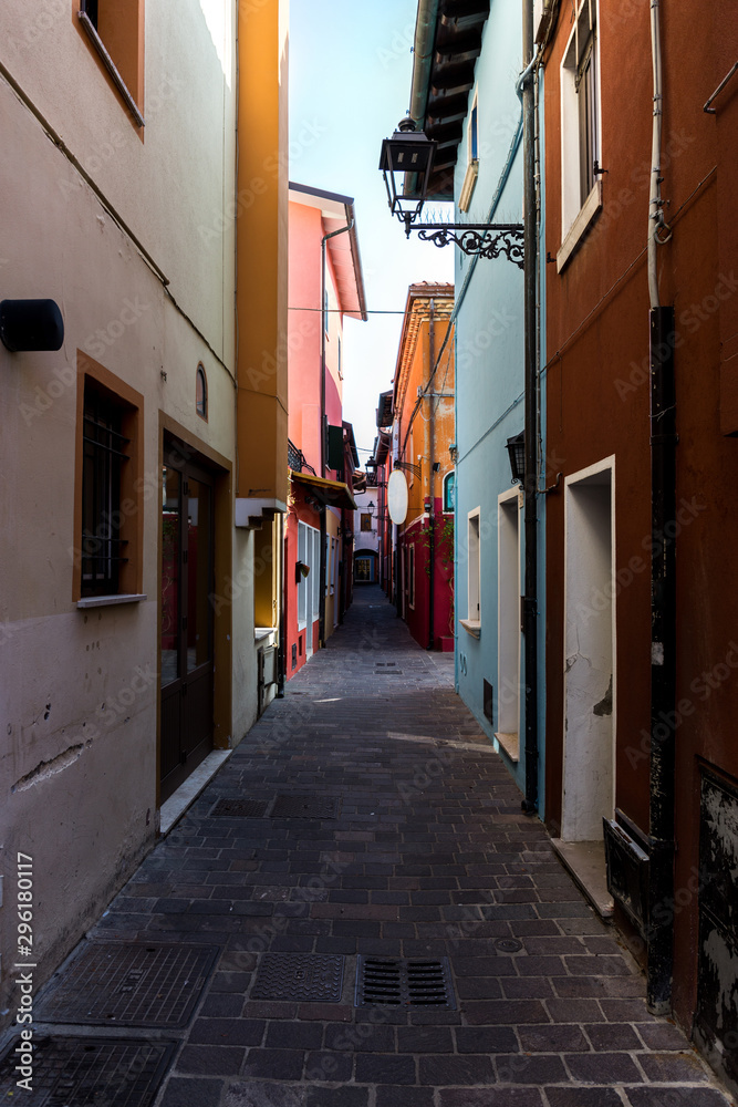 Narrow passage between colorful old buildings in city center. Caorle Italy