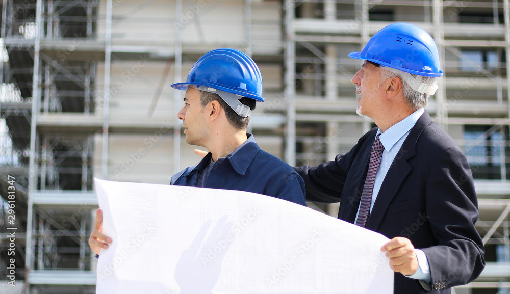 Two architect developers reviewing building plans at construction site Two architect developers reviewing building plans at construction site