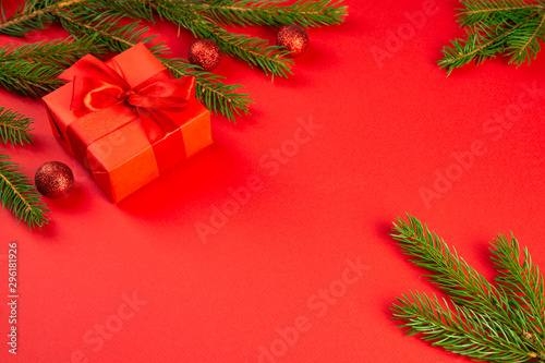 Christmas composition. Red gift  branches of spruce  red decorations on a red background. Christmas  winter  new year concept. Flat lay  top view  copy space
