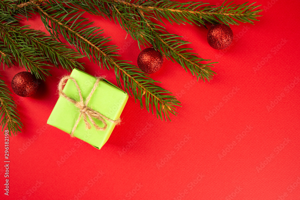 Christmas composition. Green gift, branches of spruce, red ornaments on a red background. Christmas, winter, new year concept. Flat lay, top view, copy space Christmas composition. Green gift, branches of spruce, red ornaments on a red background. Christmas, winter, new year concept. Flat lay, top view, copy space