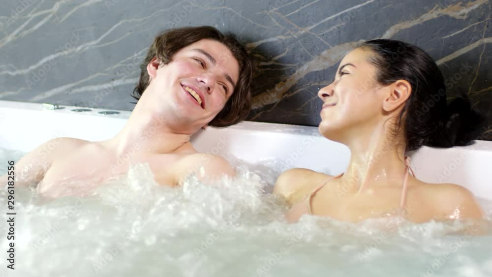 Lockdown of young diverse man and woman sitting in jacuzzi, relaxing and talking Lockdown of young diverse man and woman sitting in jacuzzi, relaxing and talking