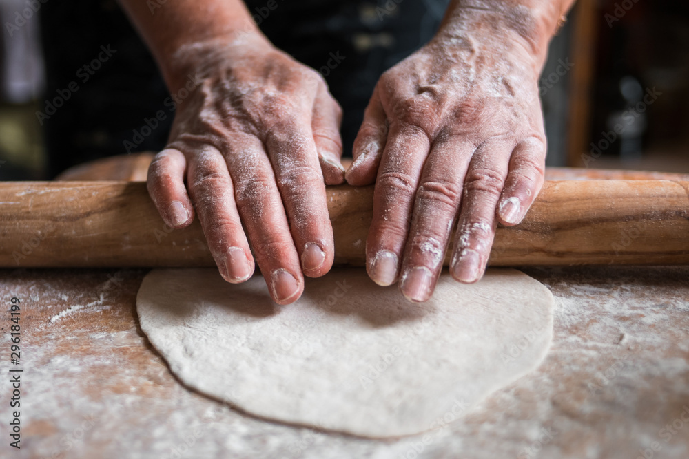 The girl's hands hold a rolling pin with flour on a wooden table. rolls out the raw dough. suitable for pizza pie cupcake paste