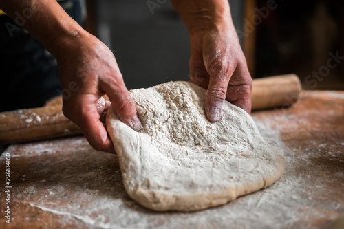 Tablou pe pânză Making dough by female hands on wooden table background close up