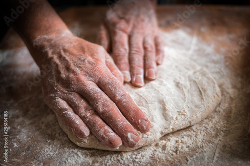 Making dough by female hands on wooden table background close up